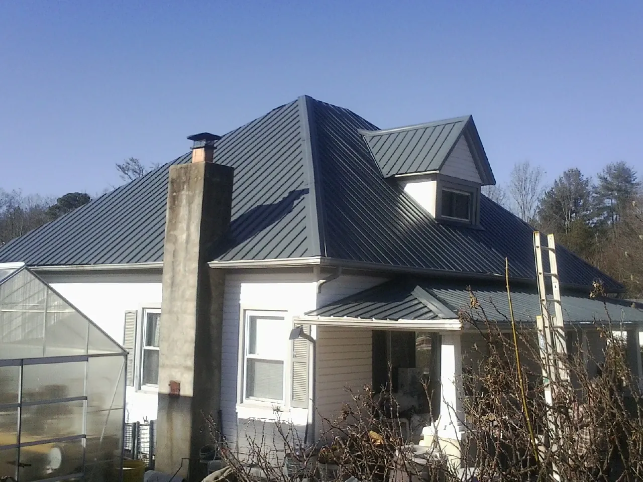 Dark blue standing seam metal roof on a white farmhouse with dormer — Slate & Tile Roof Repair by Roofing Brothers in Apalachin