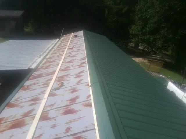 Old rusted panels beside newly installed green metal roofing — Wind Damage Roof Repair by Roofing Brothers in Apalachin