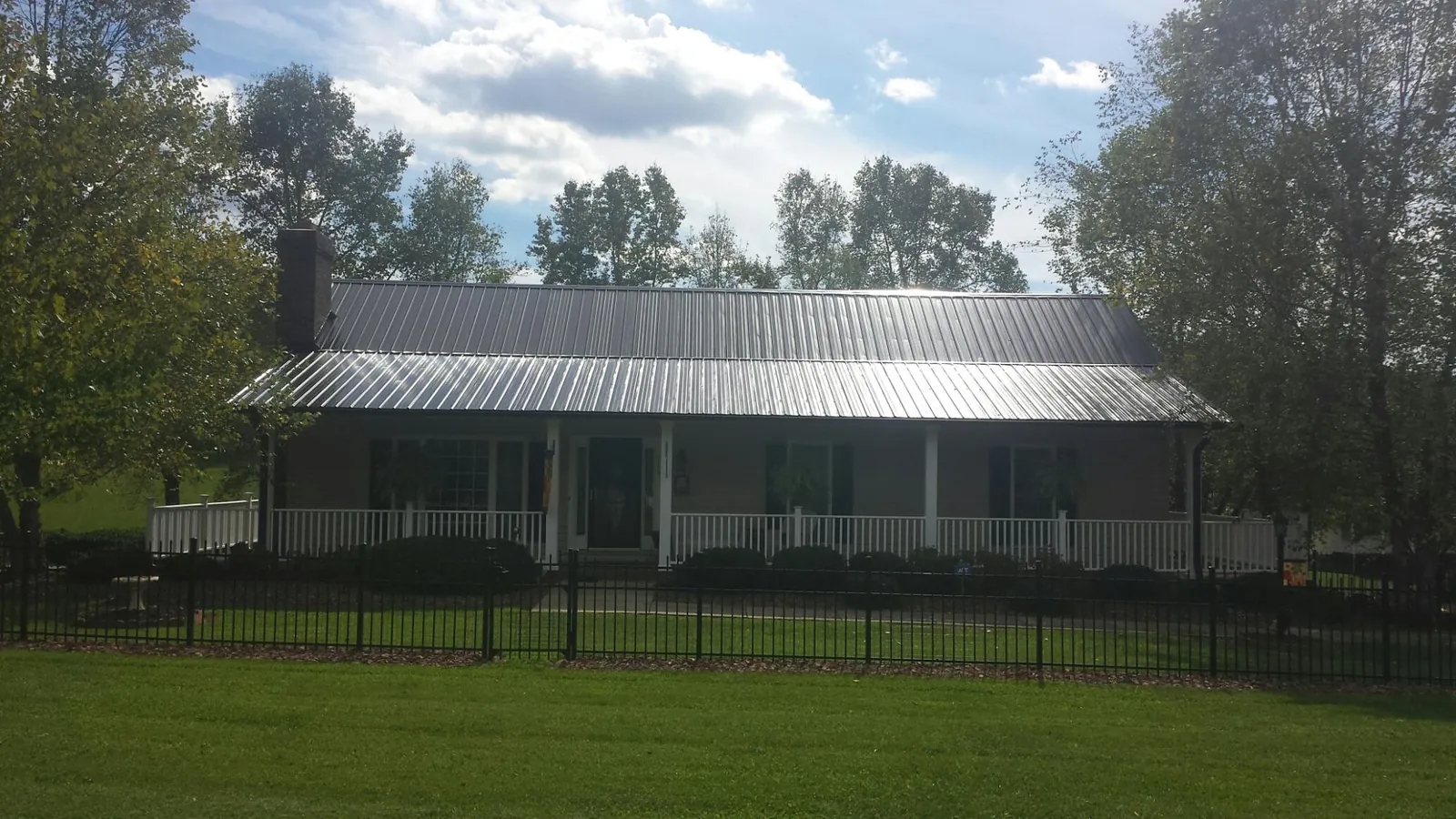 Gray metal roof on a brick ranch with a full width front porch — Gutter Guard Installation work by our crew in Apalachin