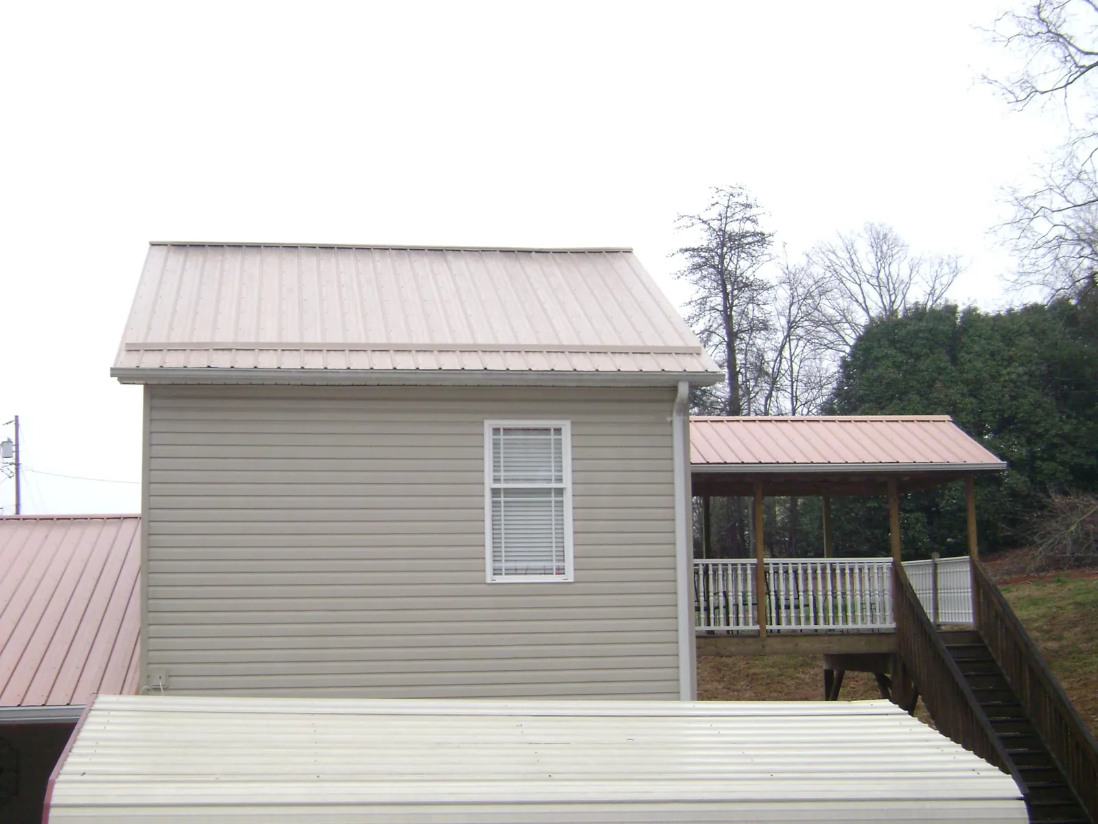 Tan metal roofs on a two story addition and attached porch, from a Roof Replacement job in Apalachin