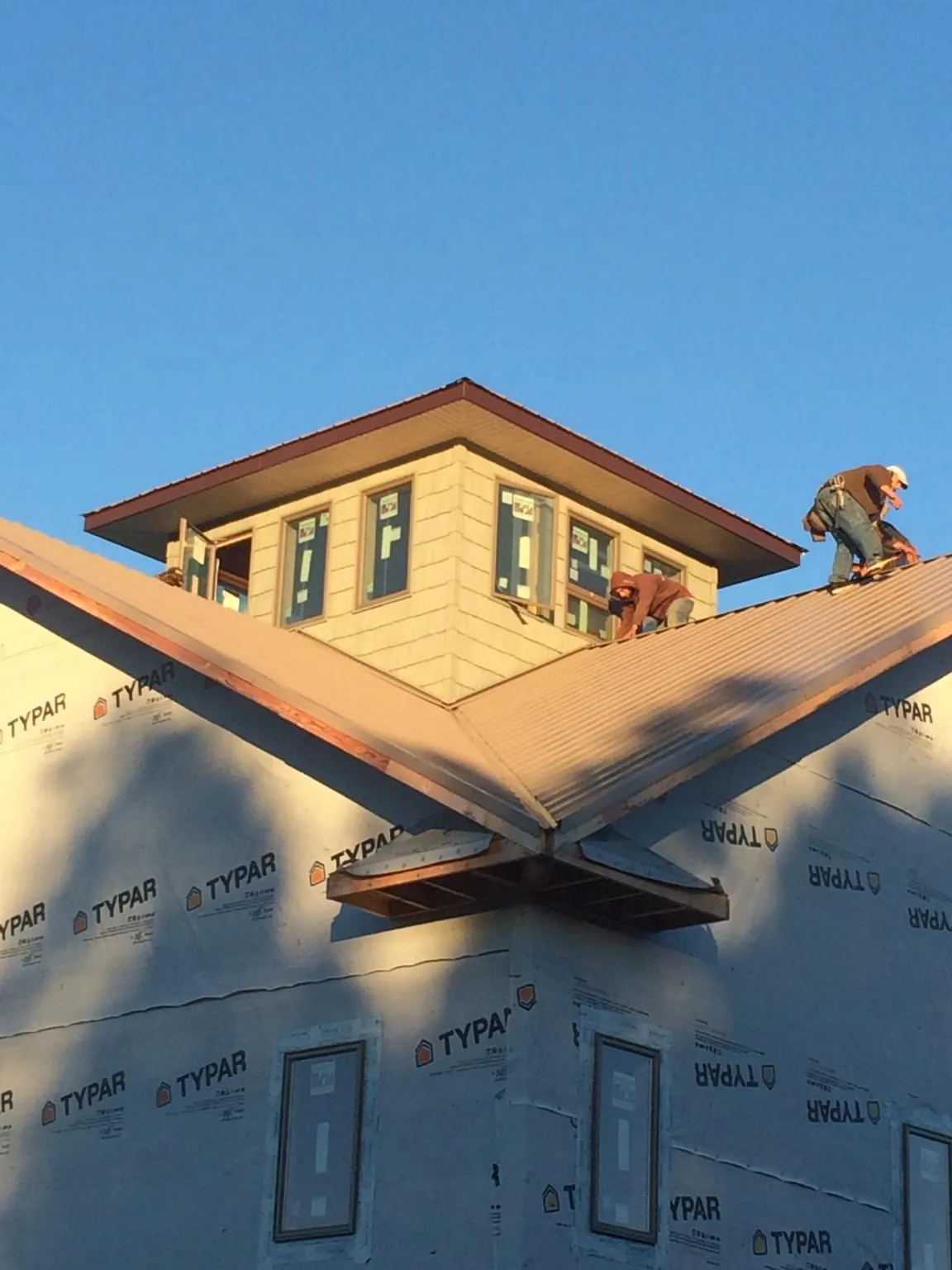 Roofers working around a rooftop cupola on a new metal roof at sunset — Roof Waterproofing in Apalachin by Roofing Brothers
